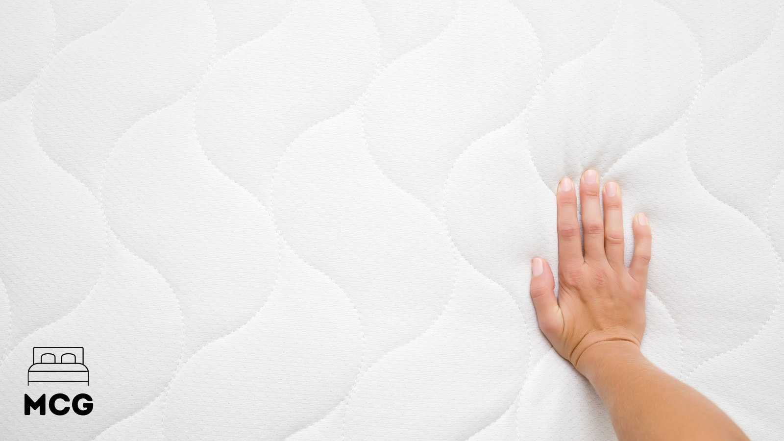 hand pressing into the surface of a mattress