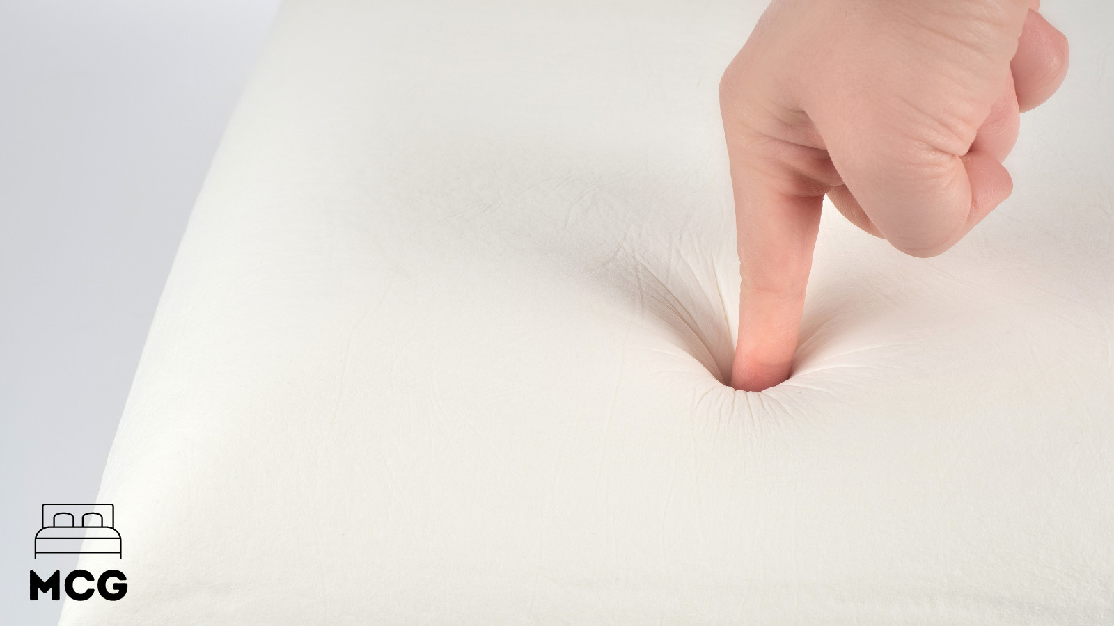 a finger pressing into a memory foam mattress