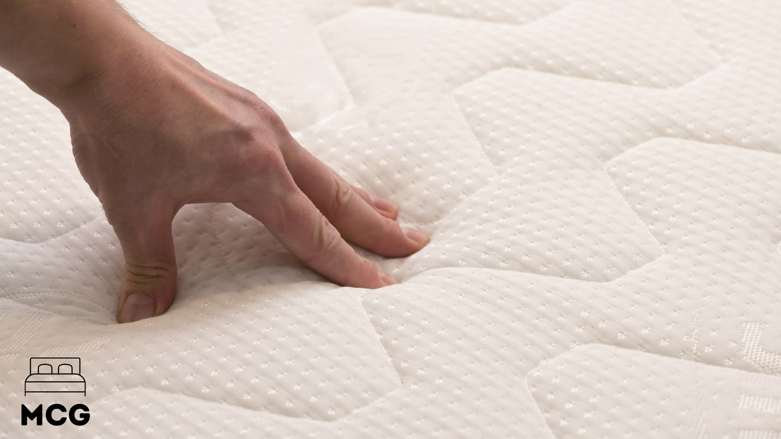 hand pressing into a memory foam mattress surface