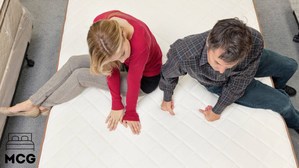 woman and man sitting on the edge of a latex mattress