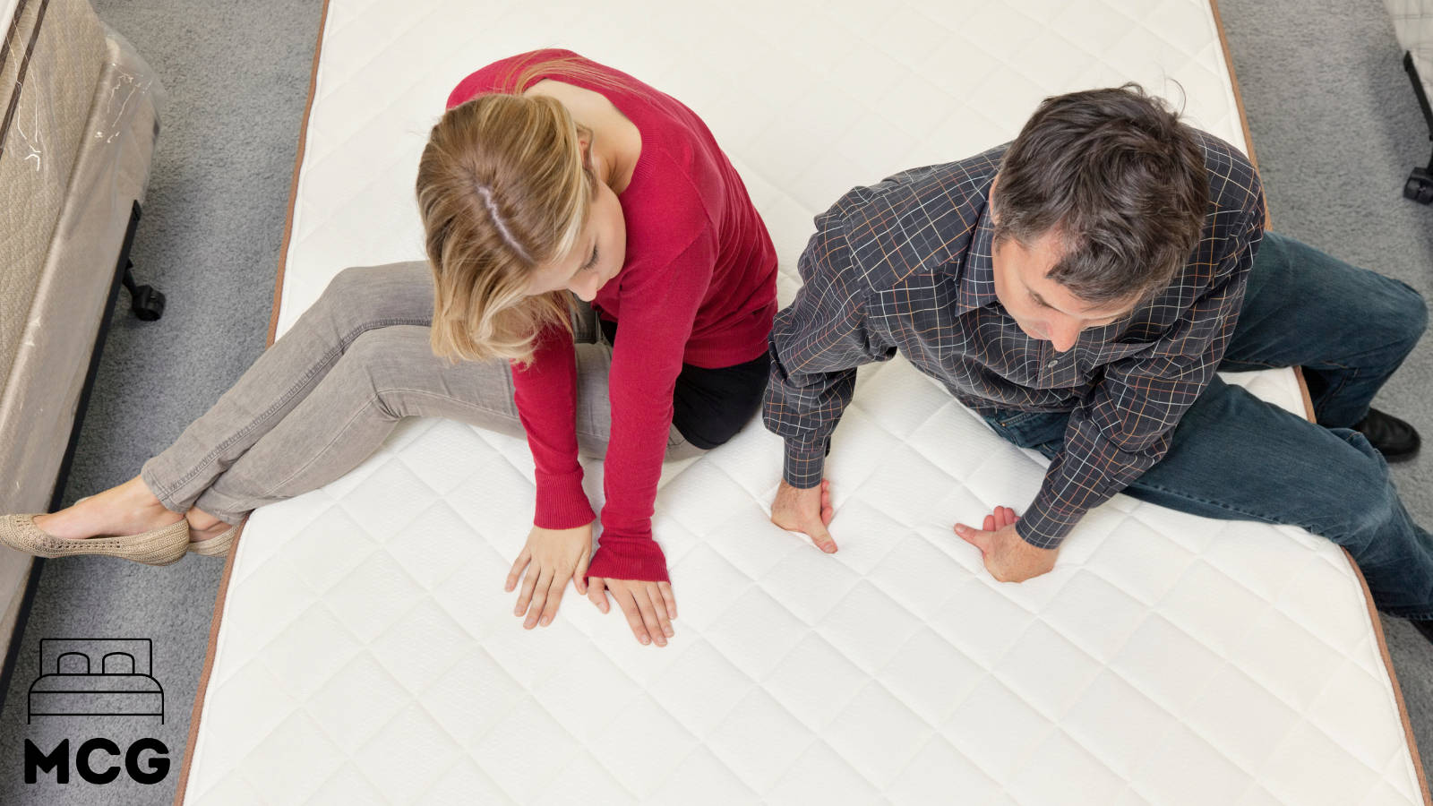 woman and man sitting on the edge of a hybrid mattress