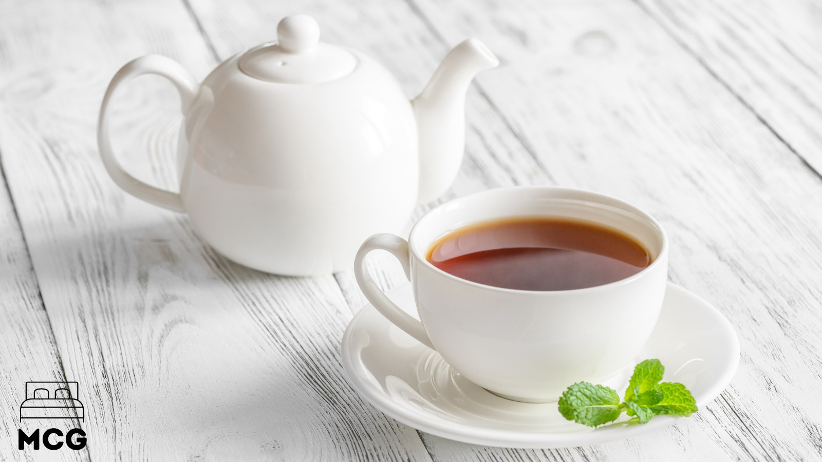 cup of black tea next to a tea pot